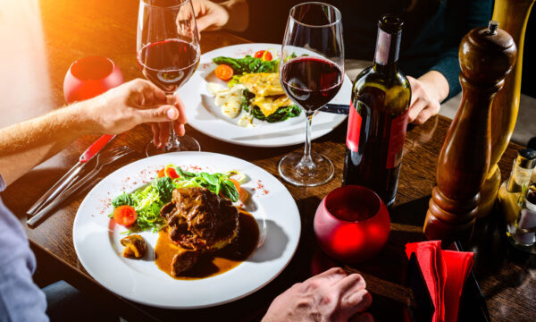 Couple having romantic dinner in a restaurant in rays of the sun Elegant dinner setting with wine and gourmet dishes.