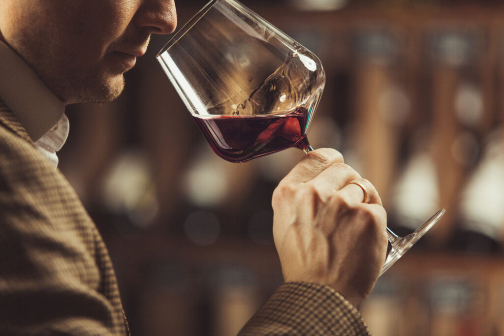 Person smelling red wine in a glass.