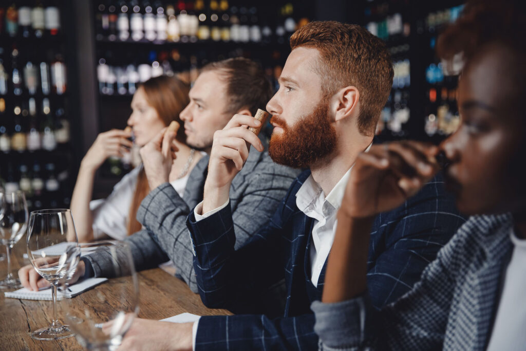 People attentively watching and tasting wine in a tasting event.