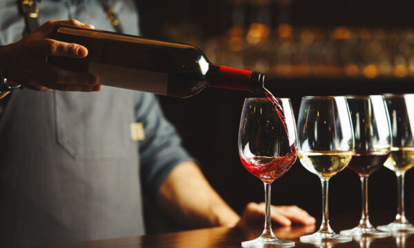 wine-degustation Person pouring red wine into a glass at a bar.